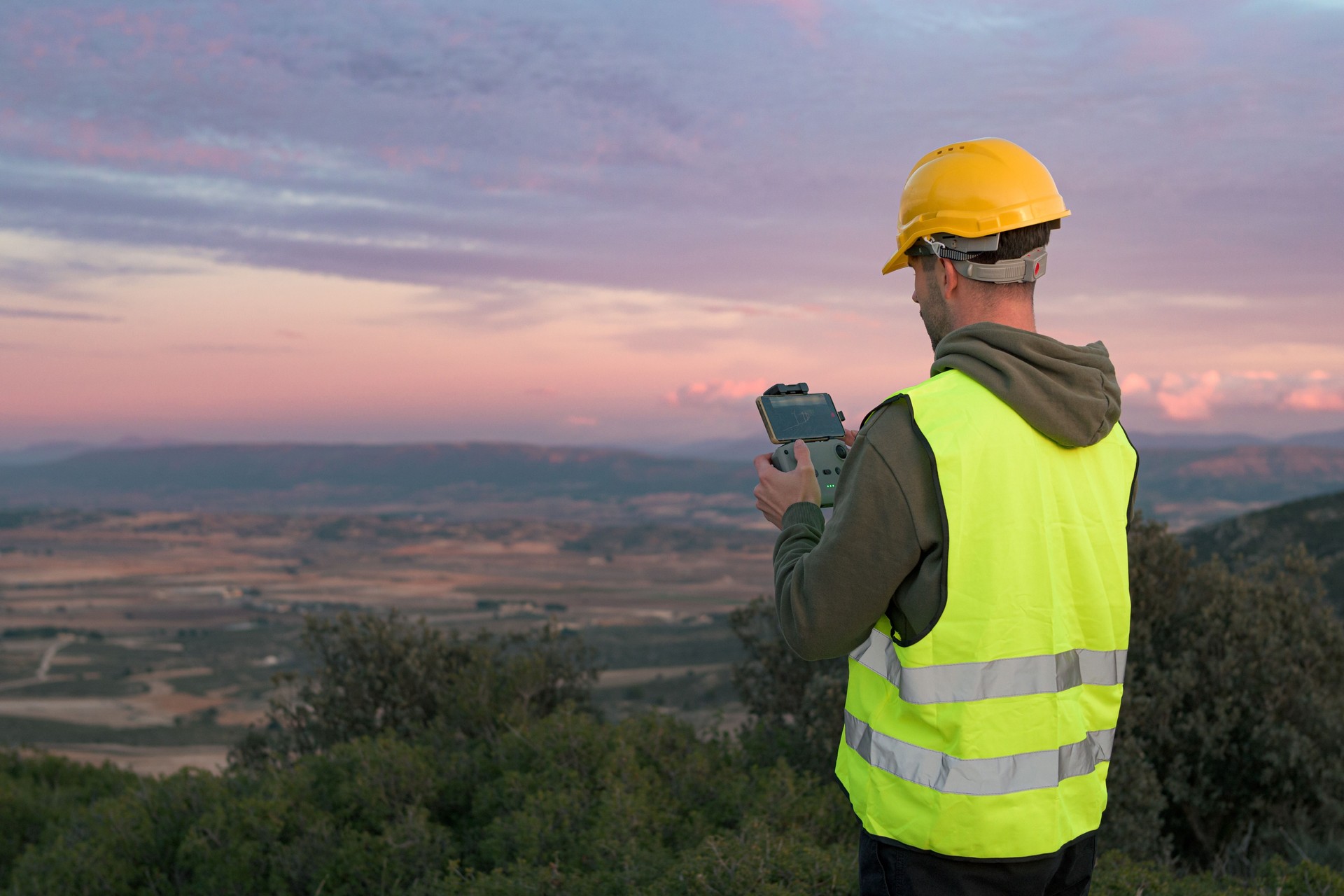 Working man directs a drone at sunset